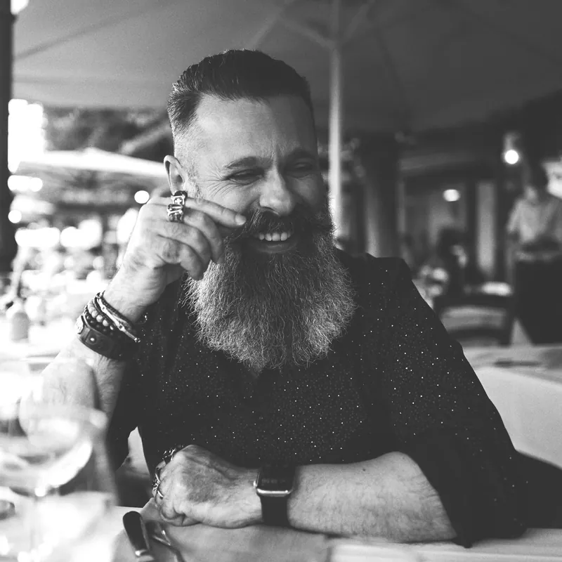 Giuseppe Irranca sorride seduto a un tavolo, fotografia in bianco e nero