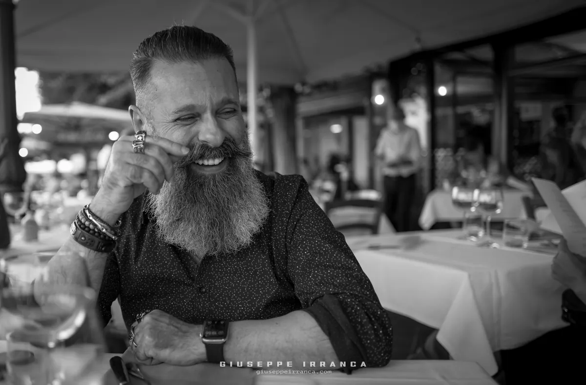 Giuseppe Irranca sorride seduto a un tavolo, fotografia in bianco e nero